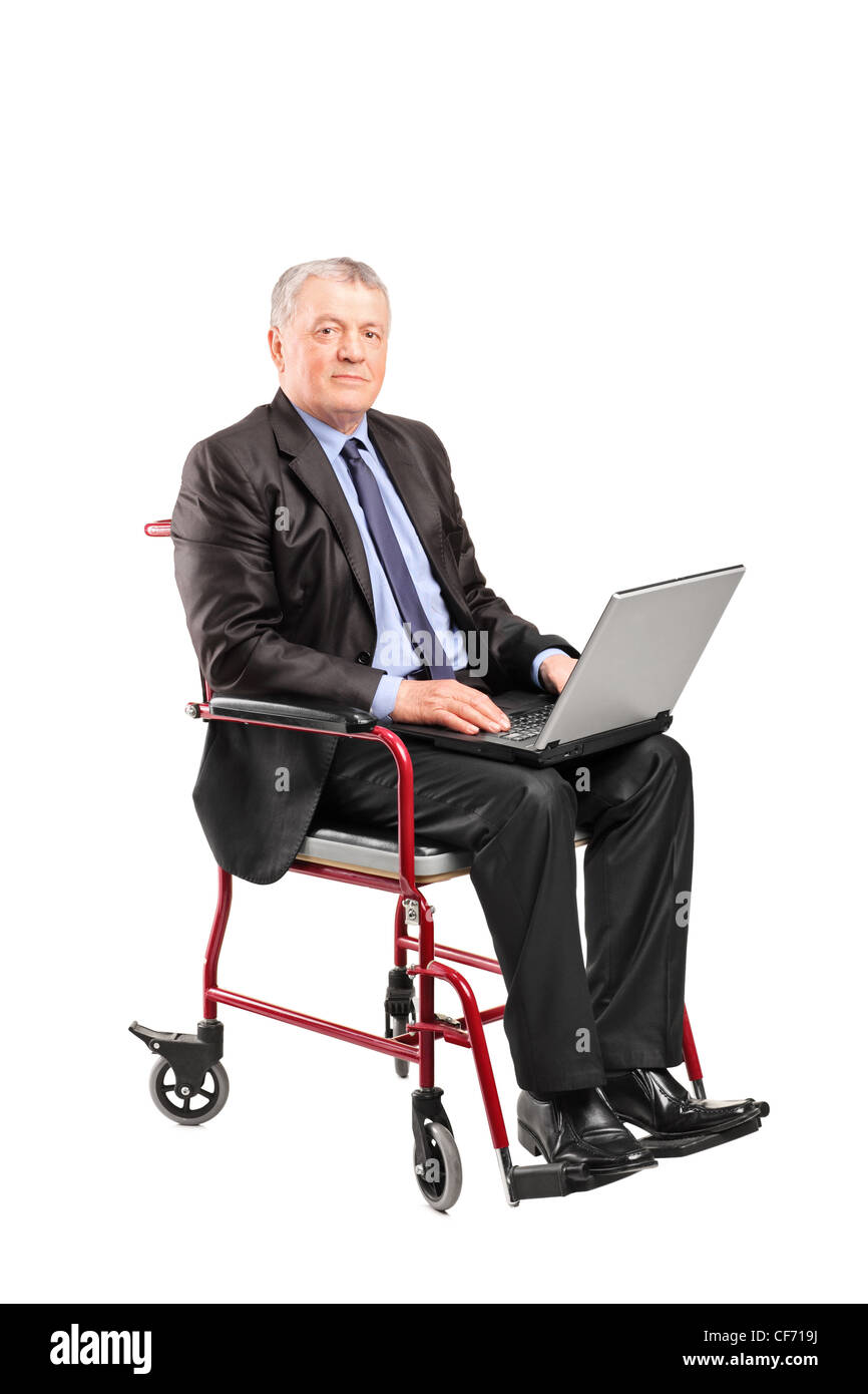 Mature businessman dans un fauteuil roulant de travailler sur un ordinateur portable isolé sur fond blanc Banque D'Images