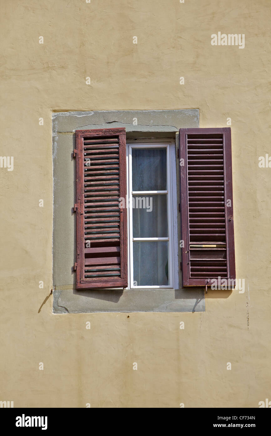 Volets en bois brun sur un mur de plâtre patiné en Toscane Banque D'Images