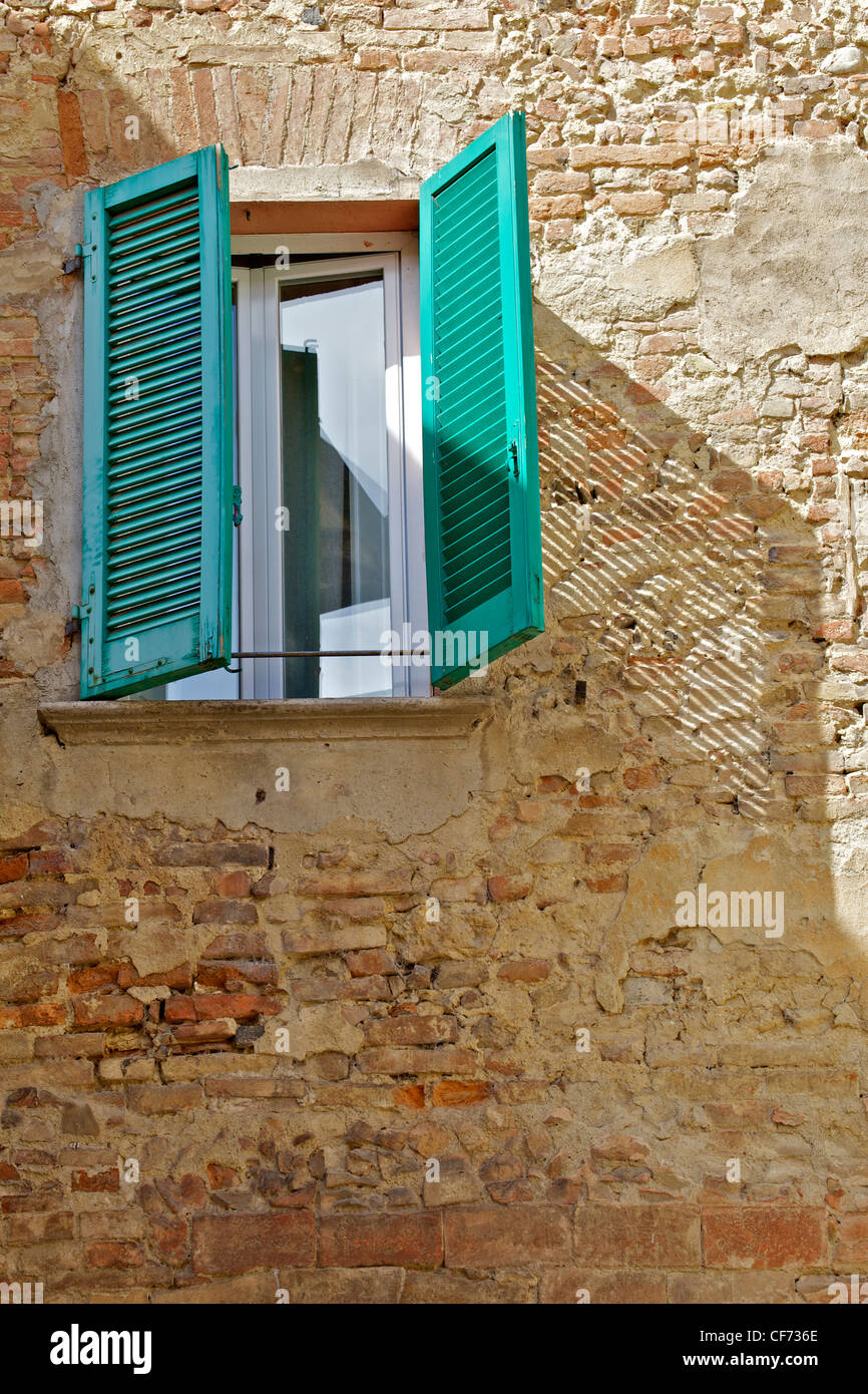 Volets de bois vert sur un mur en briques apparentes en Toscane Banque D'Images