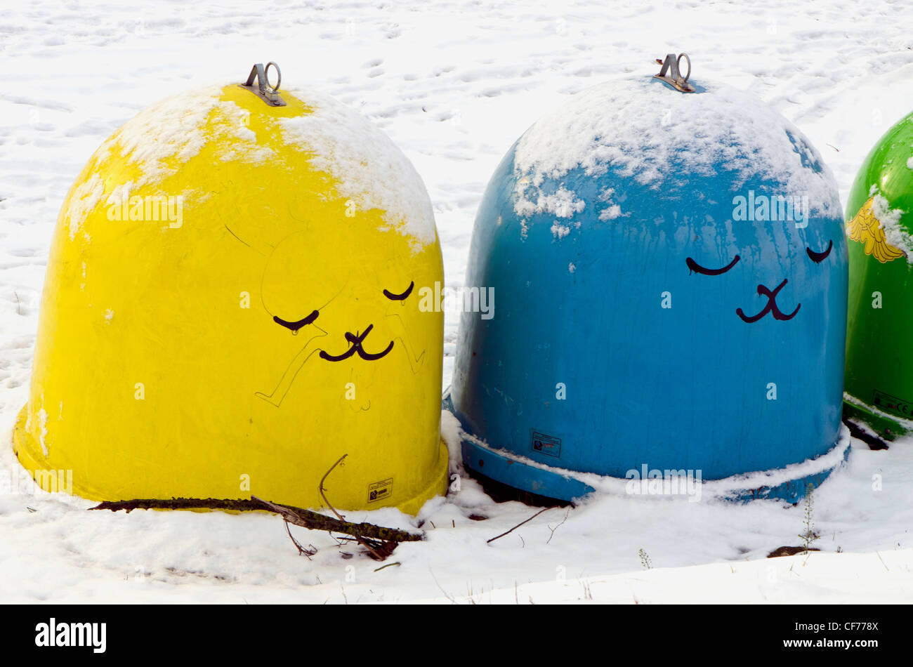 La couverture de neige des bacs en plastique pour le tri des déchets. Jaune Bleu et vert avec dessin en hiver. Banque D'Images