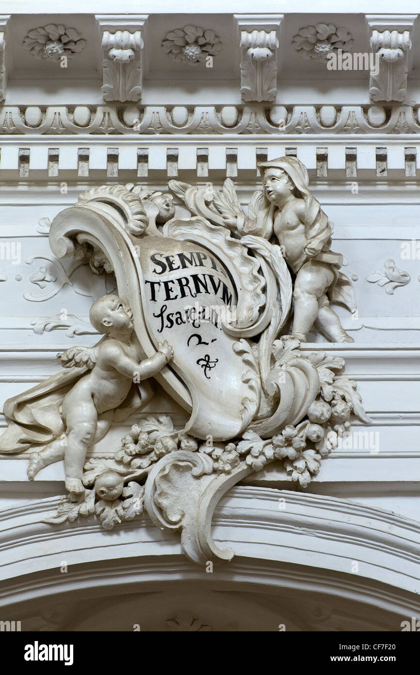 Intérieur de la Chiesa di San Carlo Borromeo al Corso dans Noto : moulage décoratif sur un arc avec putti tenant un livre Banque D'Images