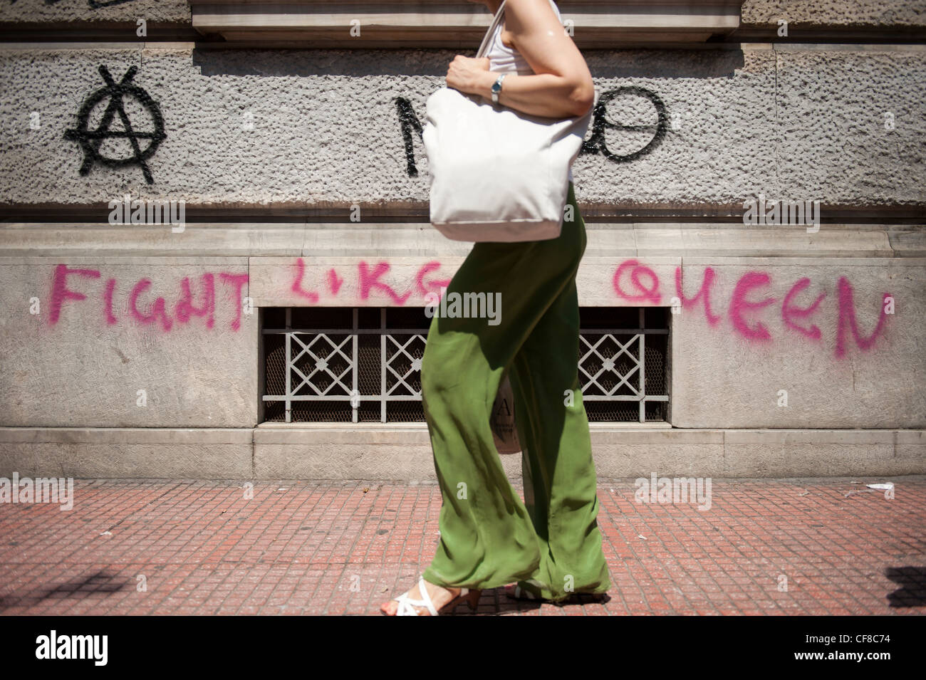 Une femme marche dans Str Panepistimiou, le centre d'Athènes par une zone d'écriture graffiti lutte comme un 'Queen' Banque D'Images