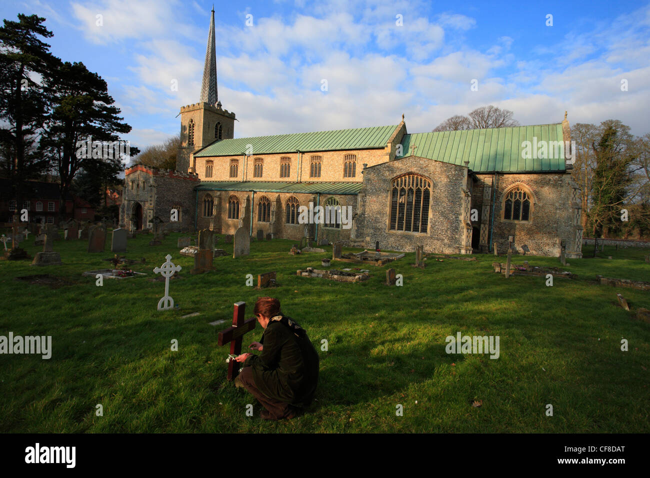 L'église St Mary à Little Walsingham à Norfolk avec une femme mettre des fleurs sur une tombe. Banque D'Images
