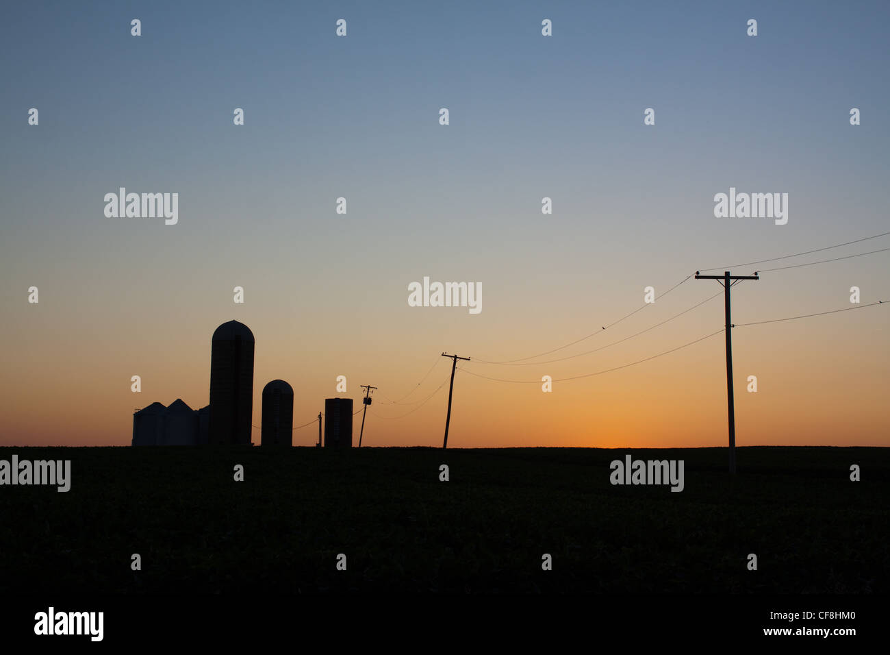 Un petit silo à grain du midwest le long d'une route peu utilisée après le coucher du soleil sur les plaines de l'Illinois. Banque D'Images