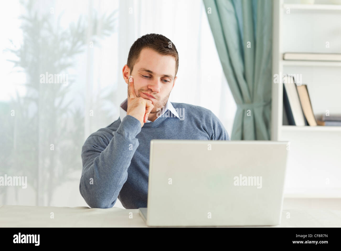 Homme d'affaires sur son ordinateur portable dans les pensées dans son homeoffice Banque D'Images