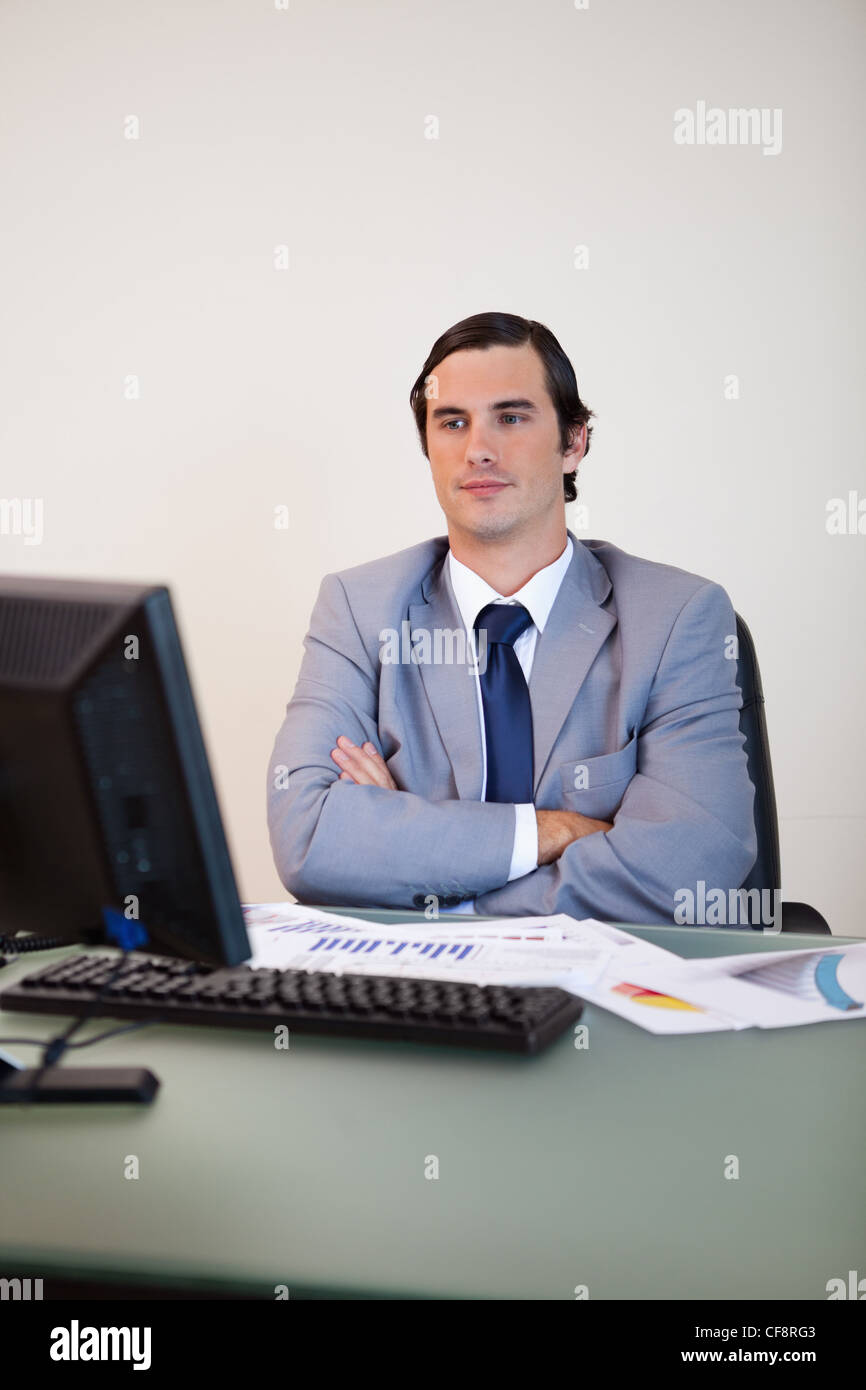 Businessman with arms folded en attente de son ordinateur Banque D'Images