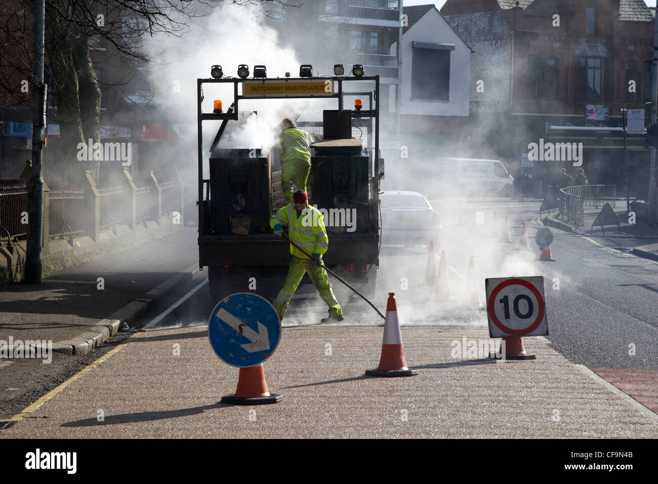 Les travailleurs de la construction routière appliquée à chaud de l'installation de revêtement routier de frottement élevé Royaume-Uni Irlande du Nord Belfast Banque D'Images