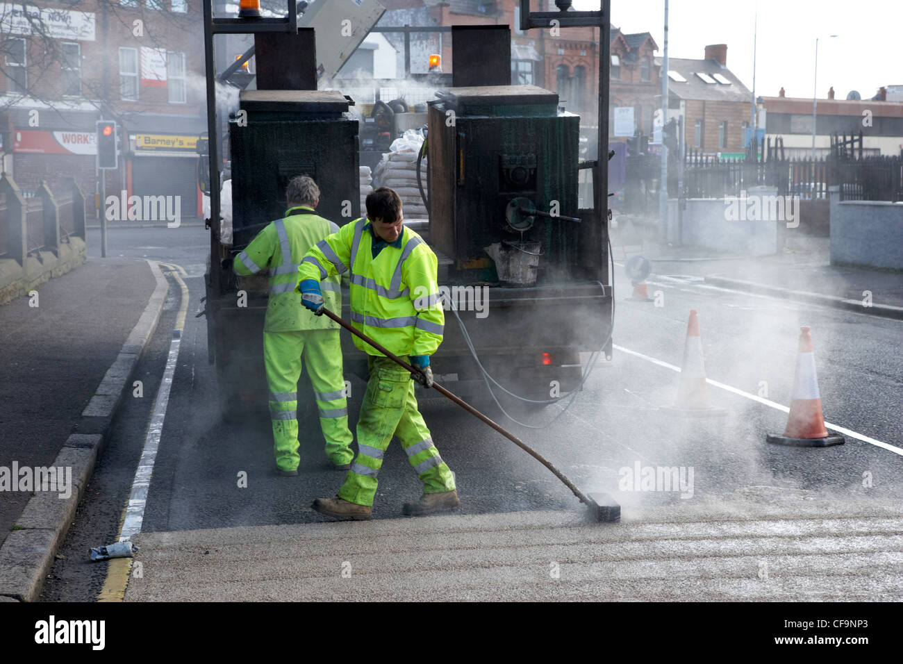 Les travailleurs de la construction routière appliquée à chaud de l'installation de revêtement routier de frottement élevé Royaume-Uni Irlande du Nord Belfast Banque D'Images