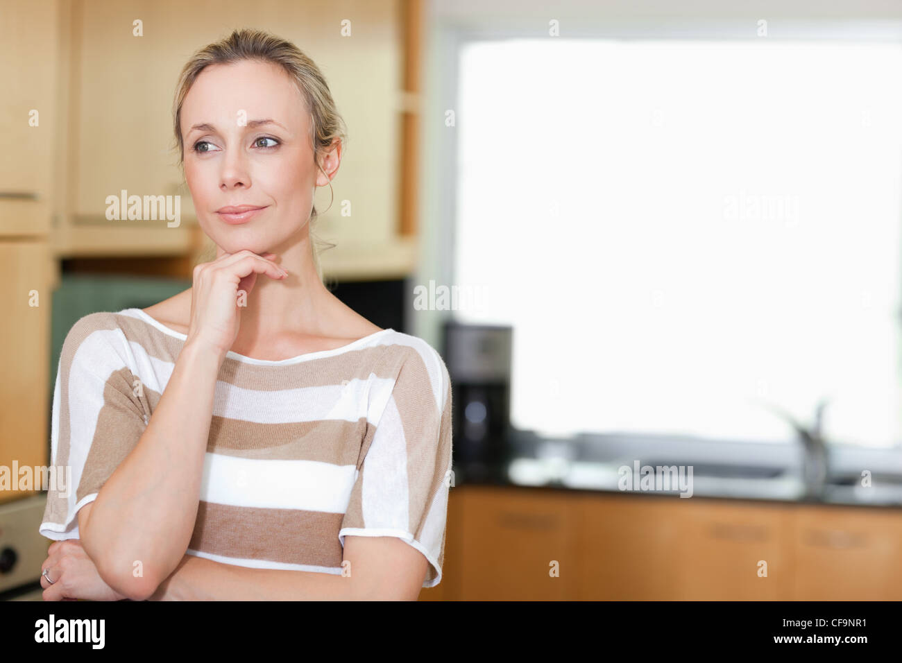 Thoughtful woman standing in kitchen Banque D'Images