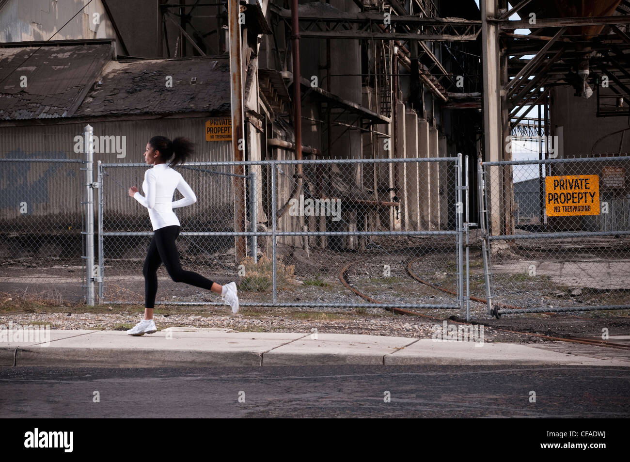 Woman running on industrial city street Banque D'Images