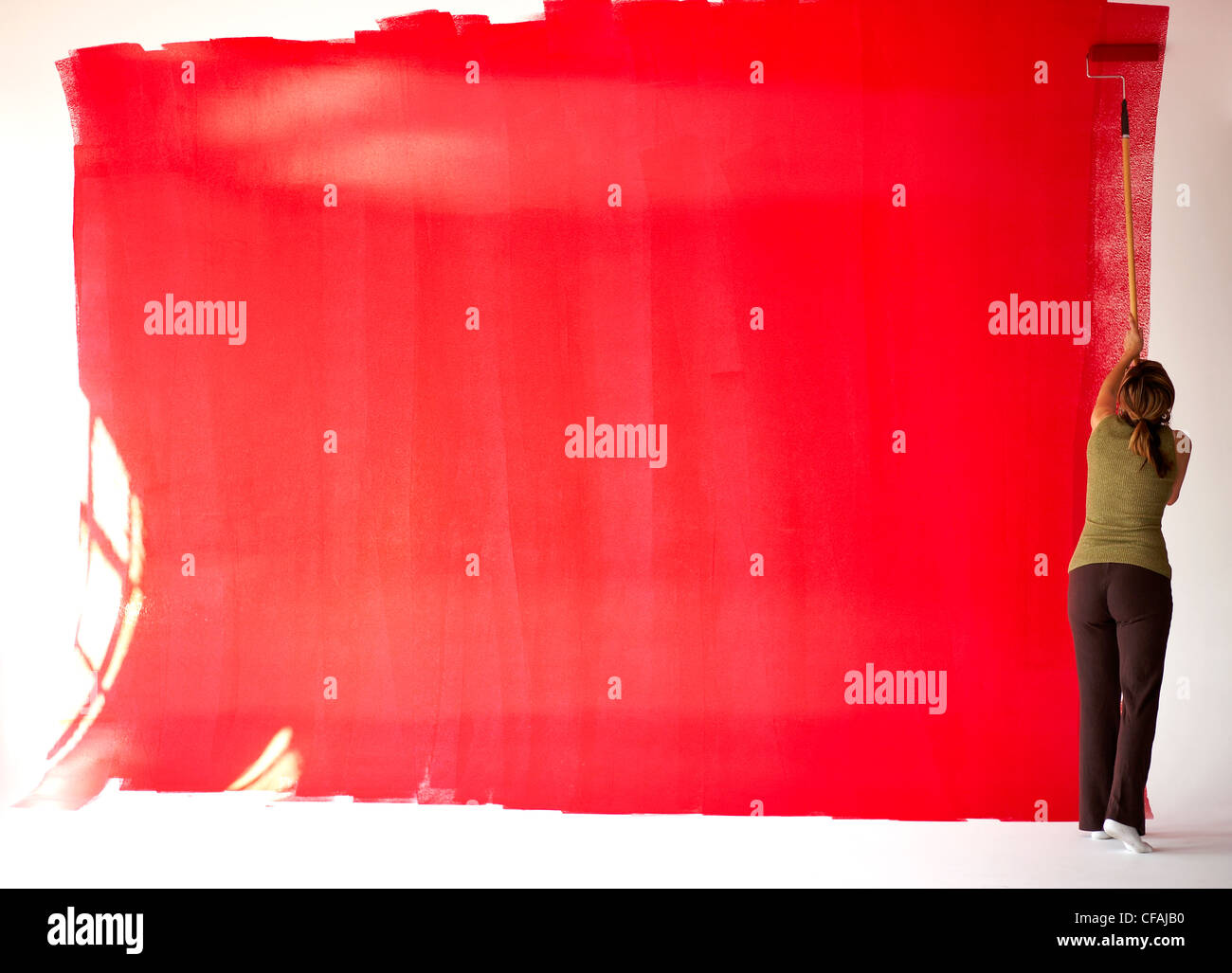31 ans femme italienne peinture rouge sur un mur blanc dans un loft, Montréal, Québec, Canada. Banque D'Images