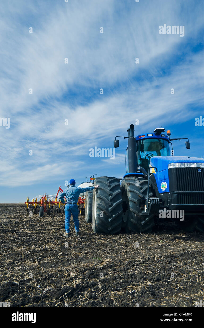 Un homme derrière le tracteur et l'air jusqu'à l'équipement d'ensemencement, près de Sainte-Agathe, Manitoba, Canada Banque D'Images