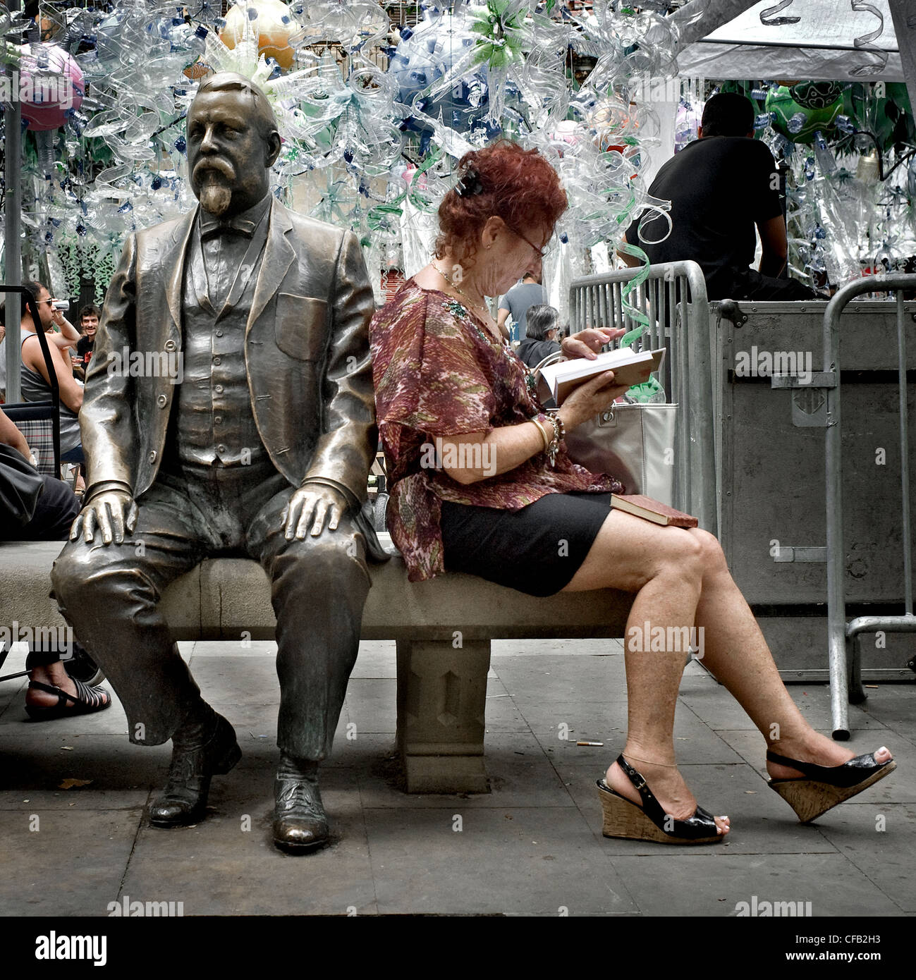 Femme lisant un livre à côté de la statue de Rovira i Trias, un architecte catalan, dans le quartier de Gracia à Barcelone. Banque D'Images