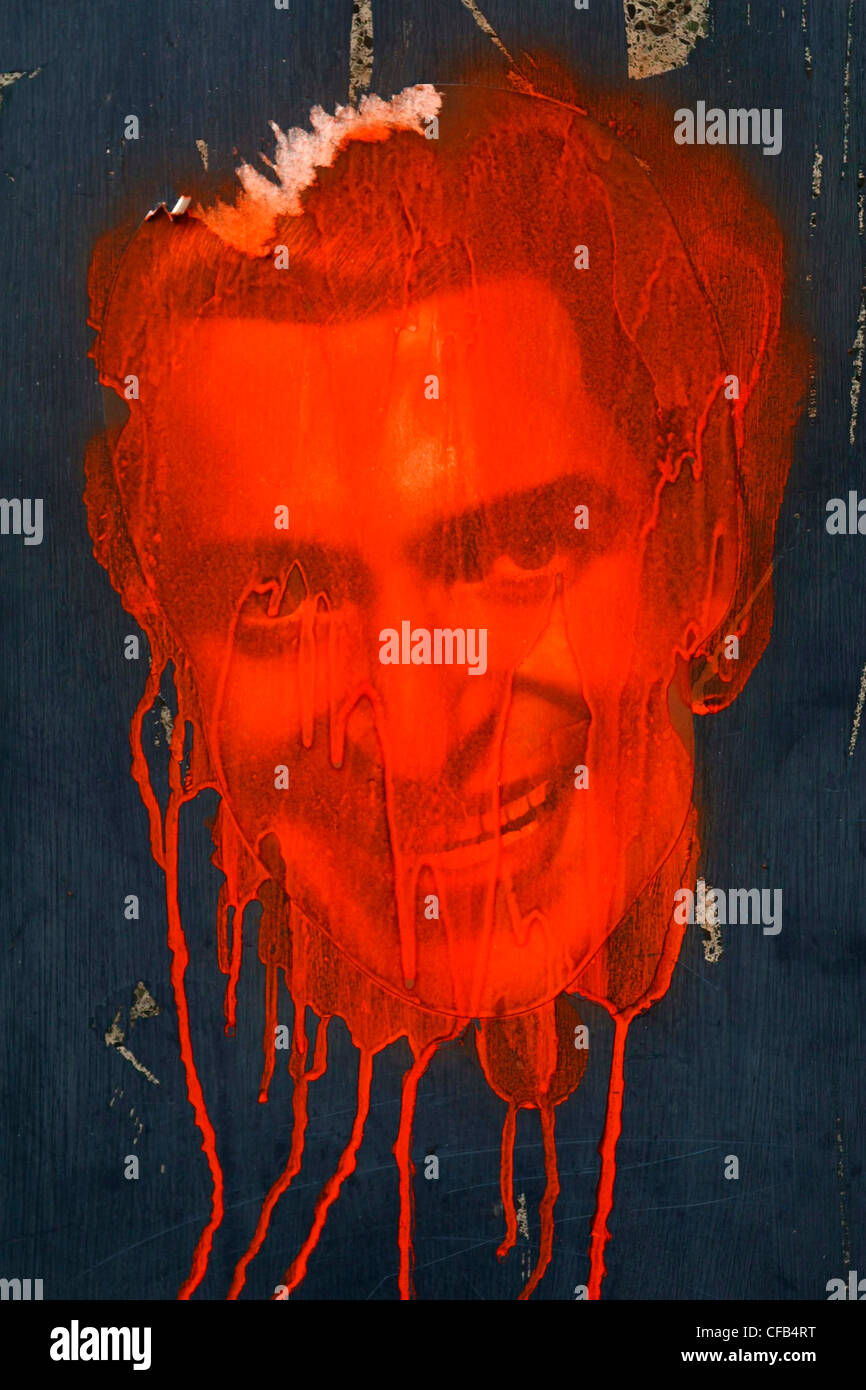 Photo de visage avec de la peinture rouge éclaboussés à travers elle sur un mur bleu Banque D'Images
