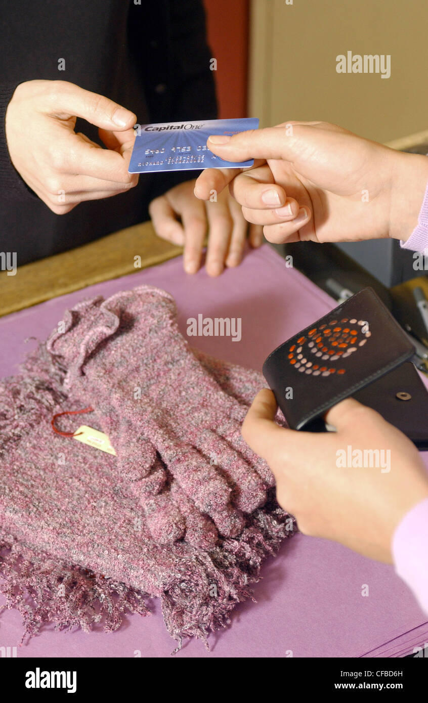 Close up of female hands payinggloves et écharpe giving credit card de la brown sac à main couture violet à homme demandez boutique Banque D'Images