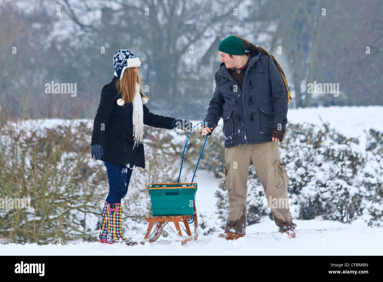 Young Caucasian man with dreadlocks et une jeune femme avec un traîneau dans la neige Banque D'Images