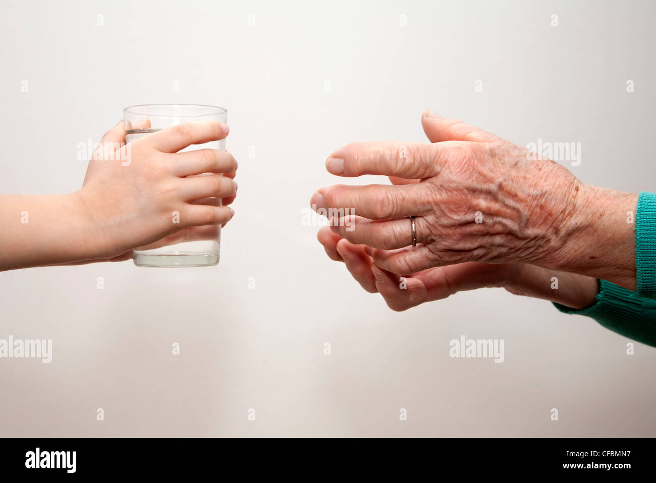 Mains de grand-mère et petit-enfant avec le verre d'eau Banque D'Images