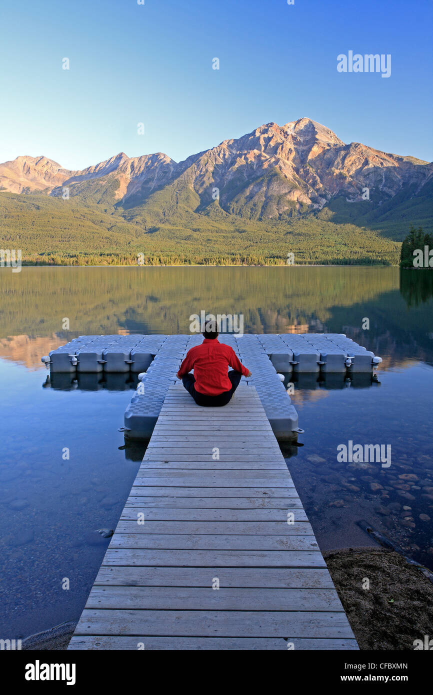 L'âge moyen homme méditant sur dock à Pyramid Lake, Jasper National Park, Alberta, Canada. Banque D'Images