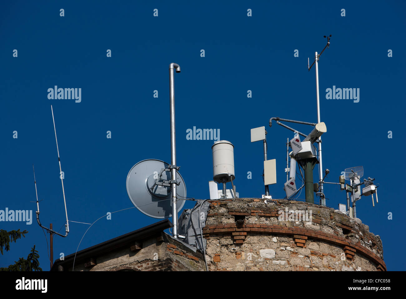 Gamme de mâts et d'antennes de téléphonie mobile sur le dessus d'une ancienne tour ronde en Italie Banque D'Images