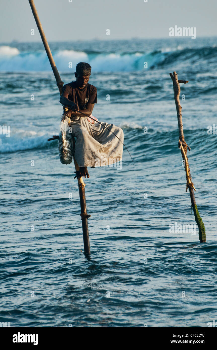 Pêcheur sur pilotis sur sa perche dans l'Océan Indien, une vieille  tradition en Midigama, Sri Lanka Photo Stock - Alamy