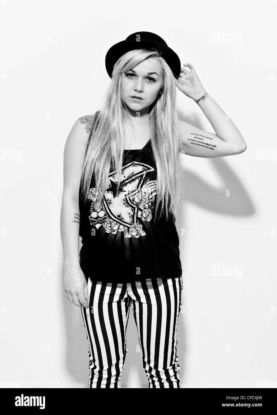 Demi-longueur noir et blanc studio portrait de femme sur fond blanc portant des jeans noir et blanc et noir chapeau melon Banque D'Images