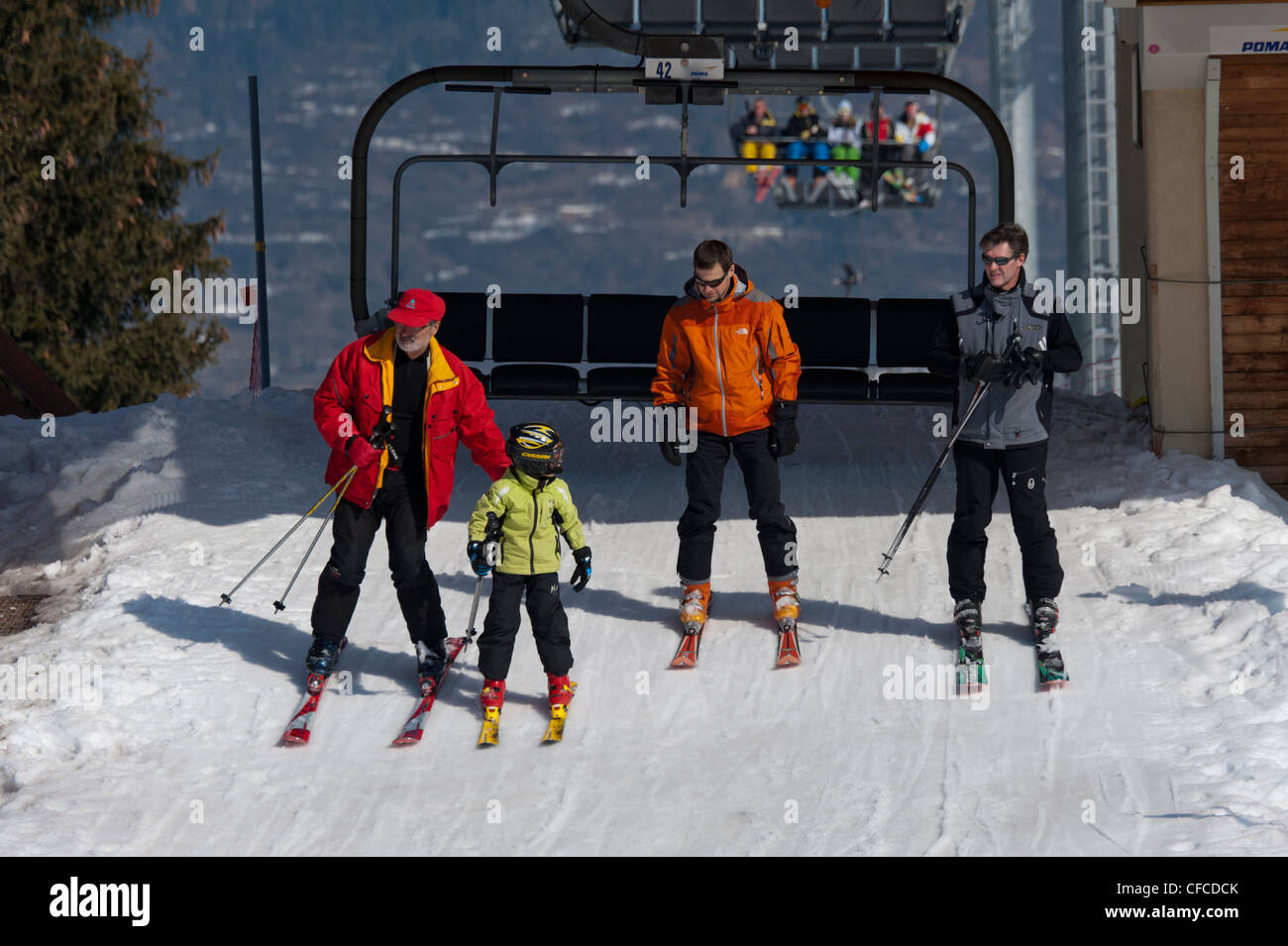 Télésiège de ski à Courchevel, domaine skiable des Trois Vallées, France. Trois adultes et un enfant d'un ascenseur. Porter des vêtements lumineux Banque D'Images