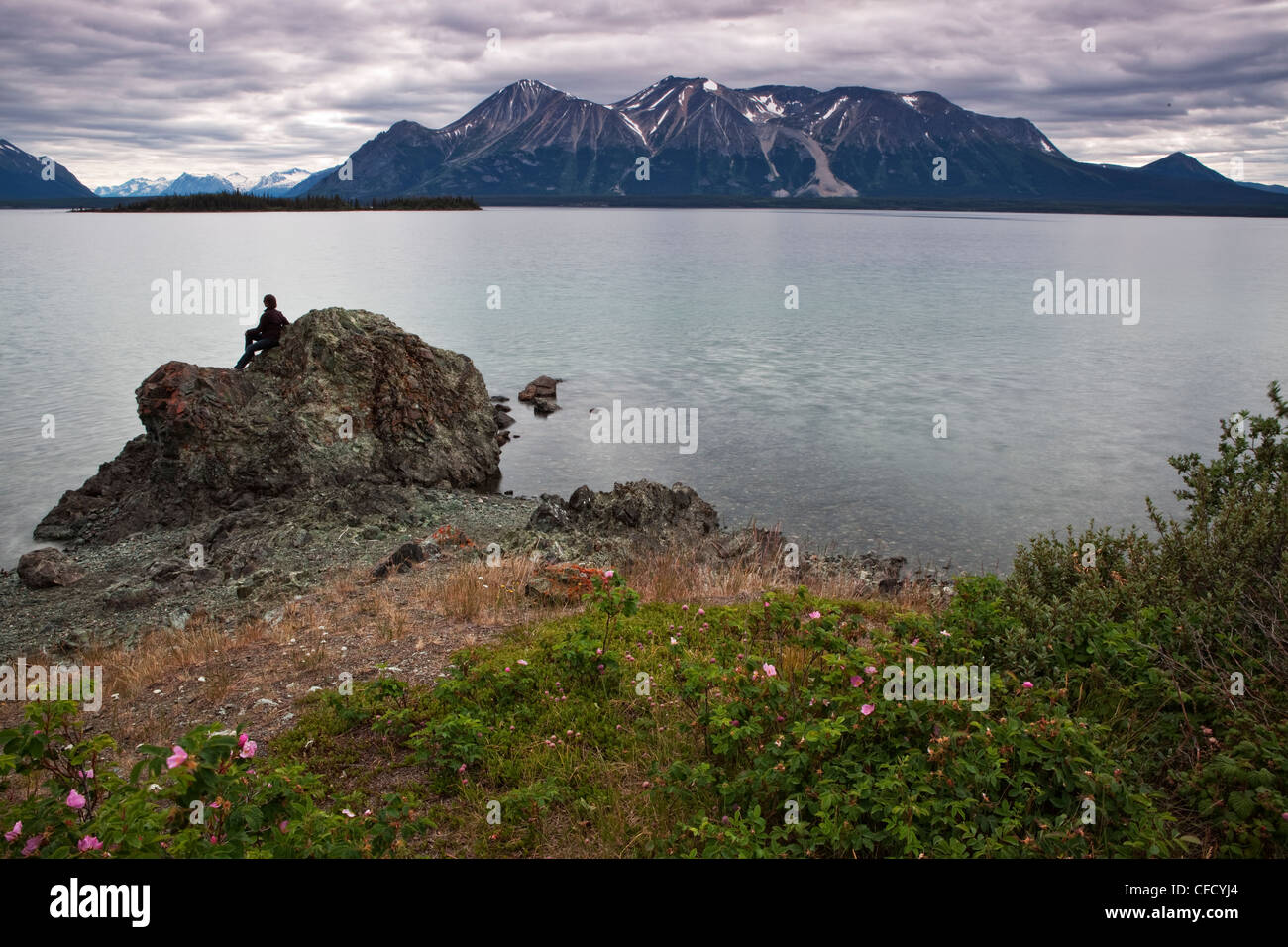 Woman sitting on rock, le lac Atlin, en Colombie-Britannique, Canada. Banque D'Images