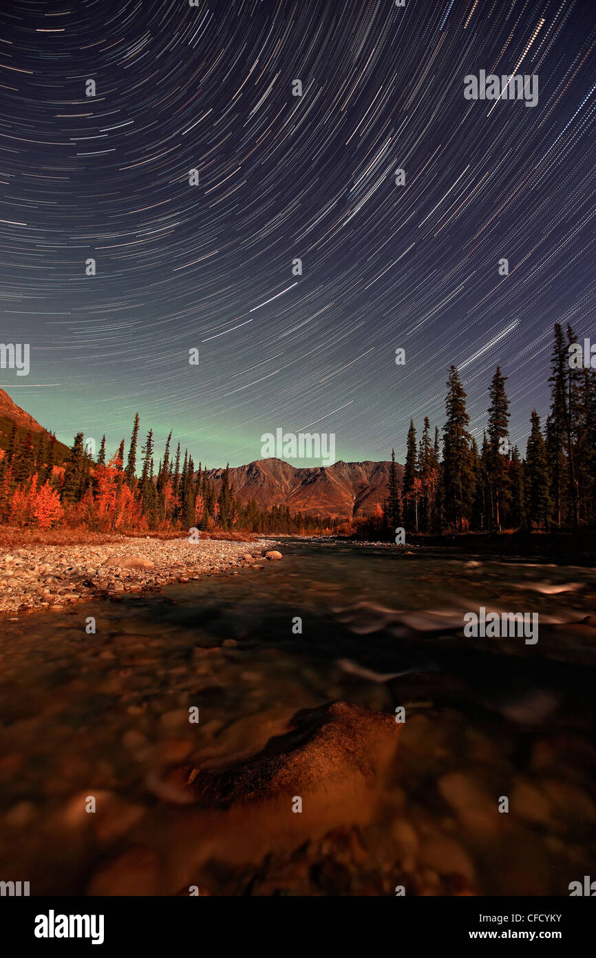 Star Trails au-dessus de la rivière Wheaton avec aurora faible vu dans la distance, Yukon, Canada. Banque D'Images