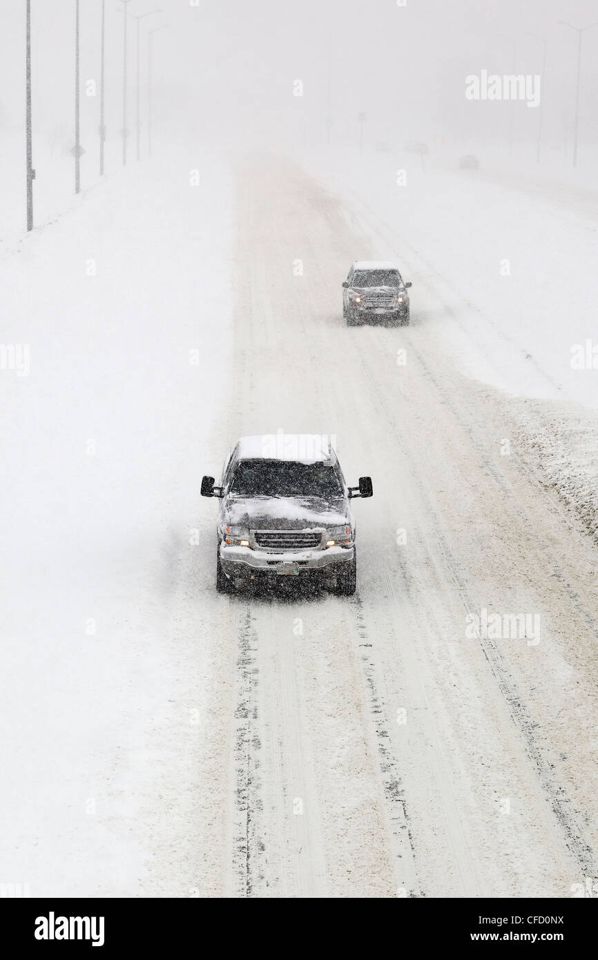 Le trafic sur une route couverte de neige, lors d'une tempête d'hiver. Winnipeg, Manitoba, Canada. Banque D'Images