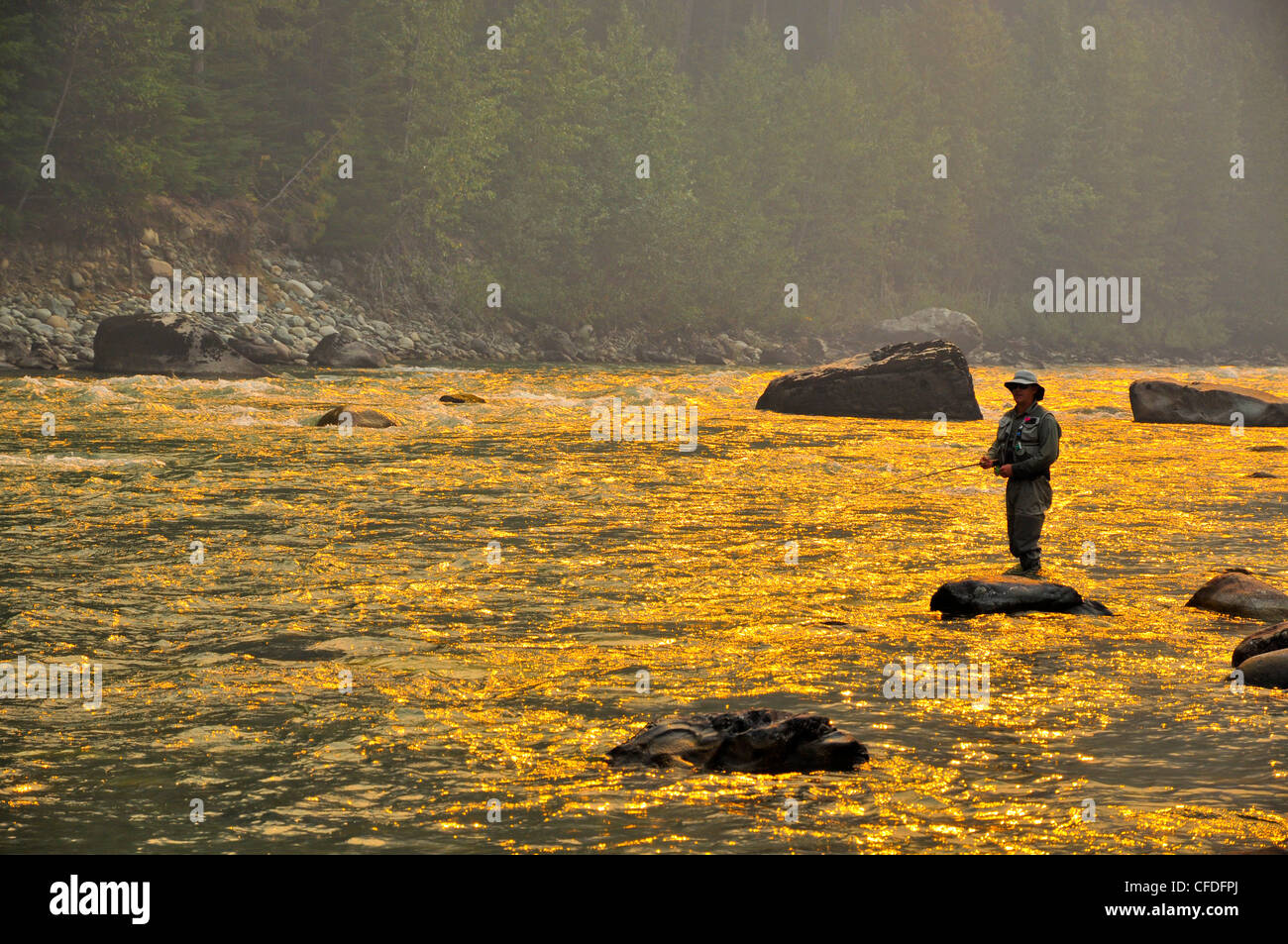 L'homme pêche de mouche, de la fumée provenant des feux de forêt, Dean River, Colombie-Britannique, Canada Banque D'Images