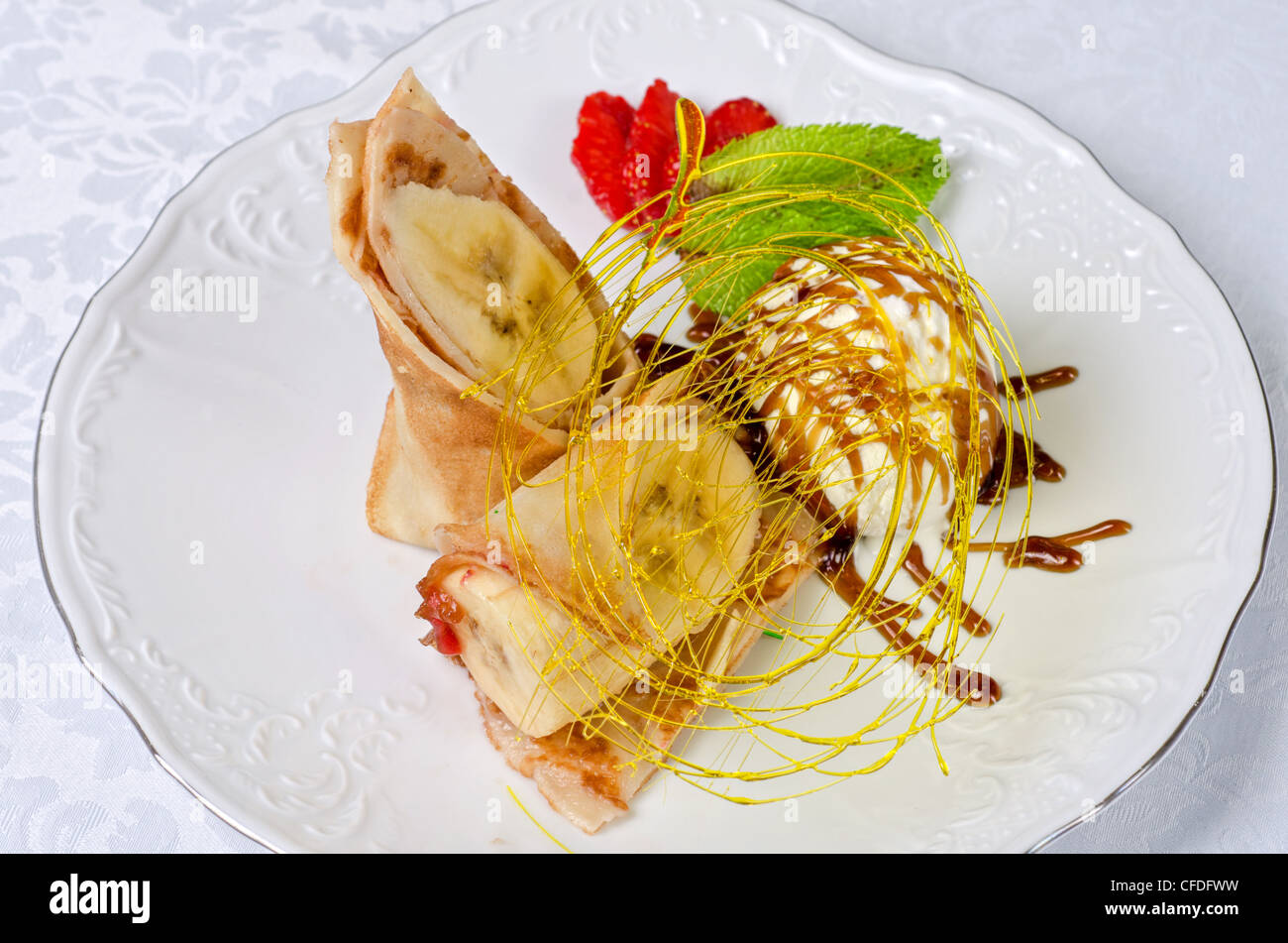 Dessert de crêpes au banane, glace, caramel, fraise et menthe Banque D'Images