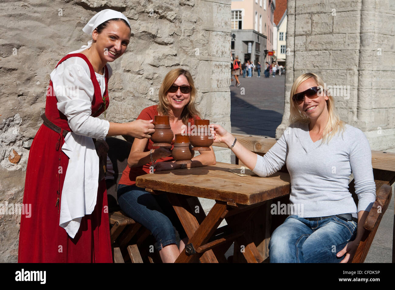 Serveuse en costume médiéval et les touristes avec des tasses à café restaurant Olde Hansa en place de l'hôtel de ville (Raekoja plats), Tallin Banque D'Images