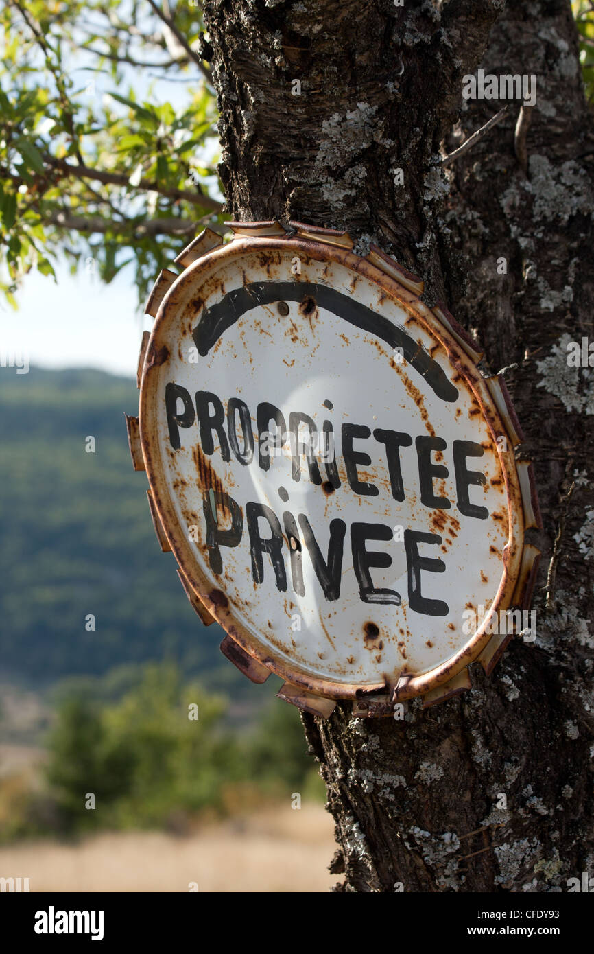 Une vieille enseigne rouillée sur un arbre dans la campagne provençale, 'Proprietee privee' (propriété privée), Provence, France. Banque D'Images