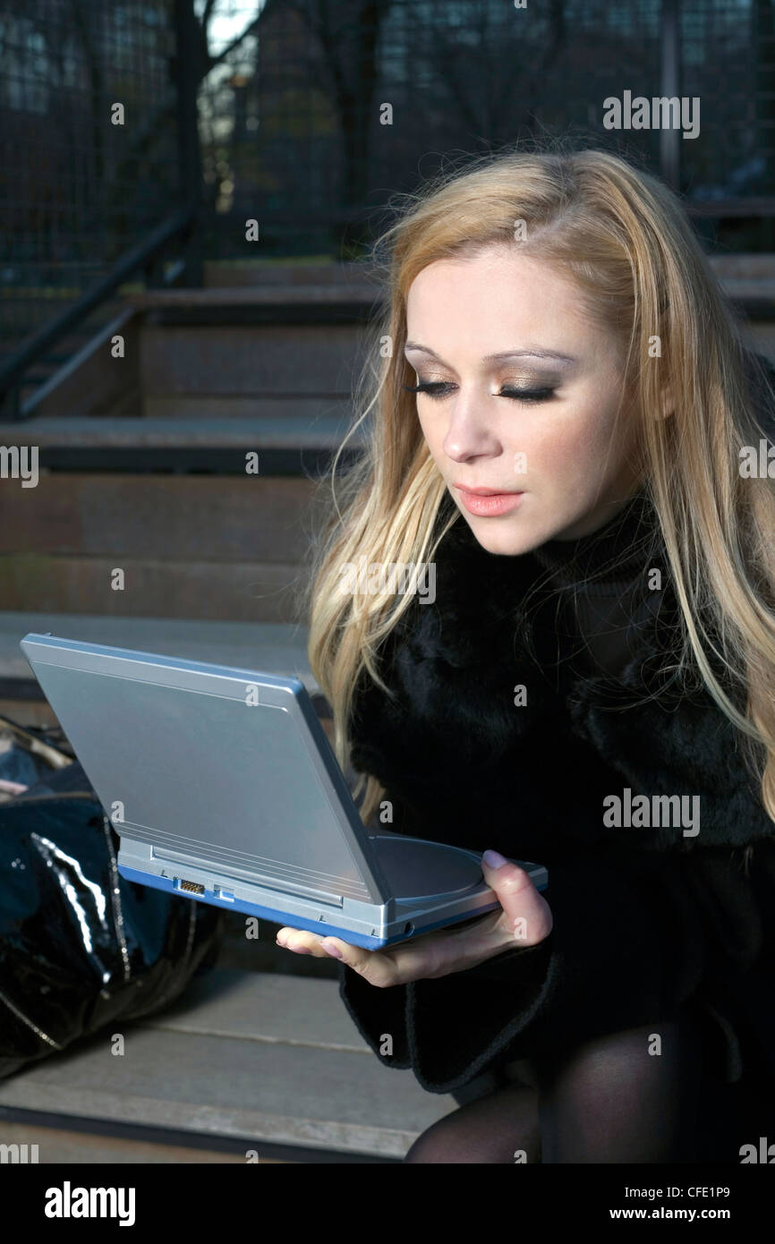Une femme de race blanche à l'extérieur avec son appareil électronique. Banque D'Images