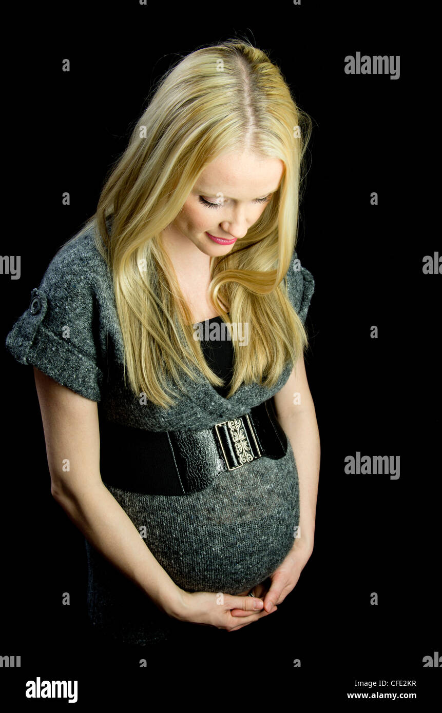 Une image de la maternité d'une jolie femme blonde, contre une clé faible (noir) en toile de fond. Banque D'Images