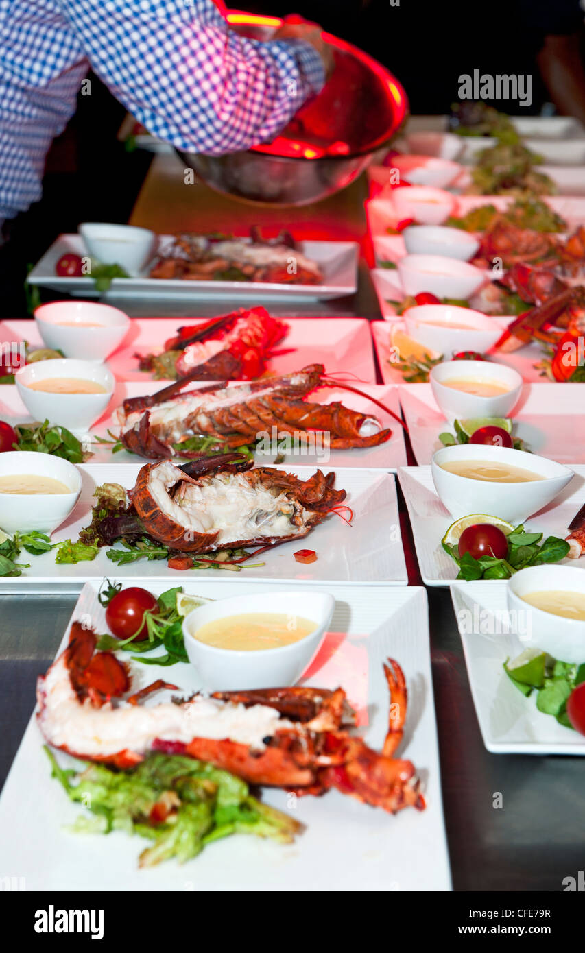 Les plaques avec le homard en préparation dans un restaurant par un chef de cuisine, un bol de salade de saisie Banque D'Images