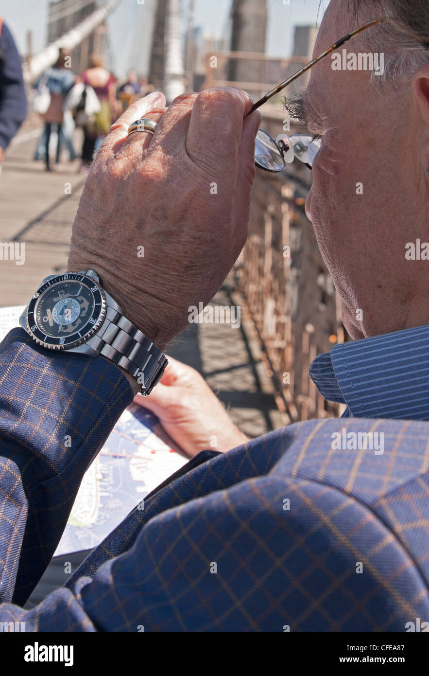 Un homme bien habillé sur le pont de Brooklyn studies sa carte. Banque D'Images