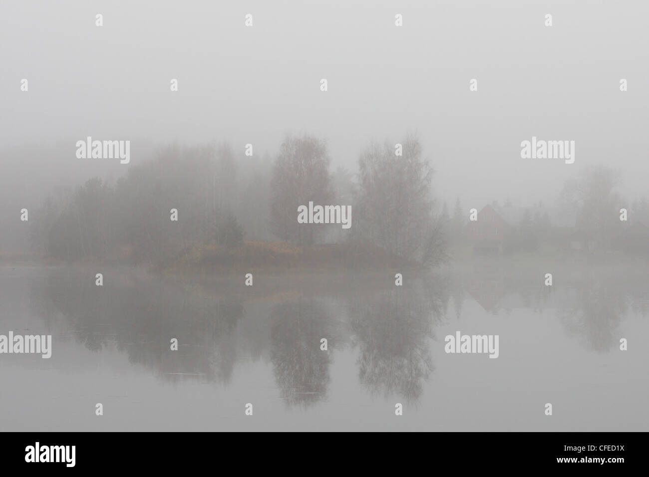 Un brouillard épais au bord du lac. Maison peut être vu à l'autre côté de la rive. Banque D'Images