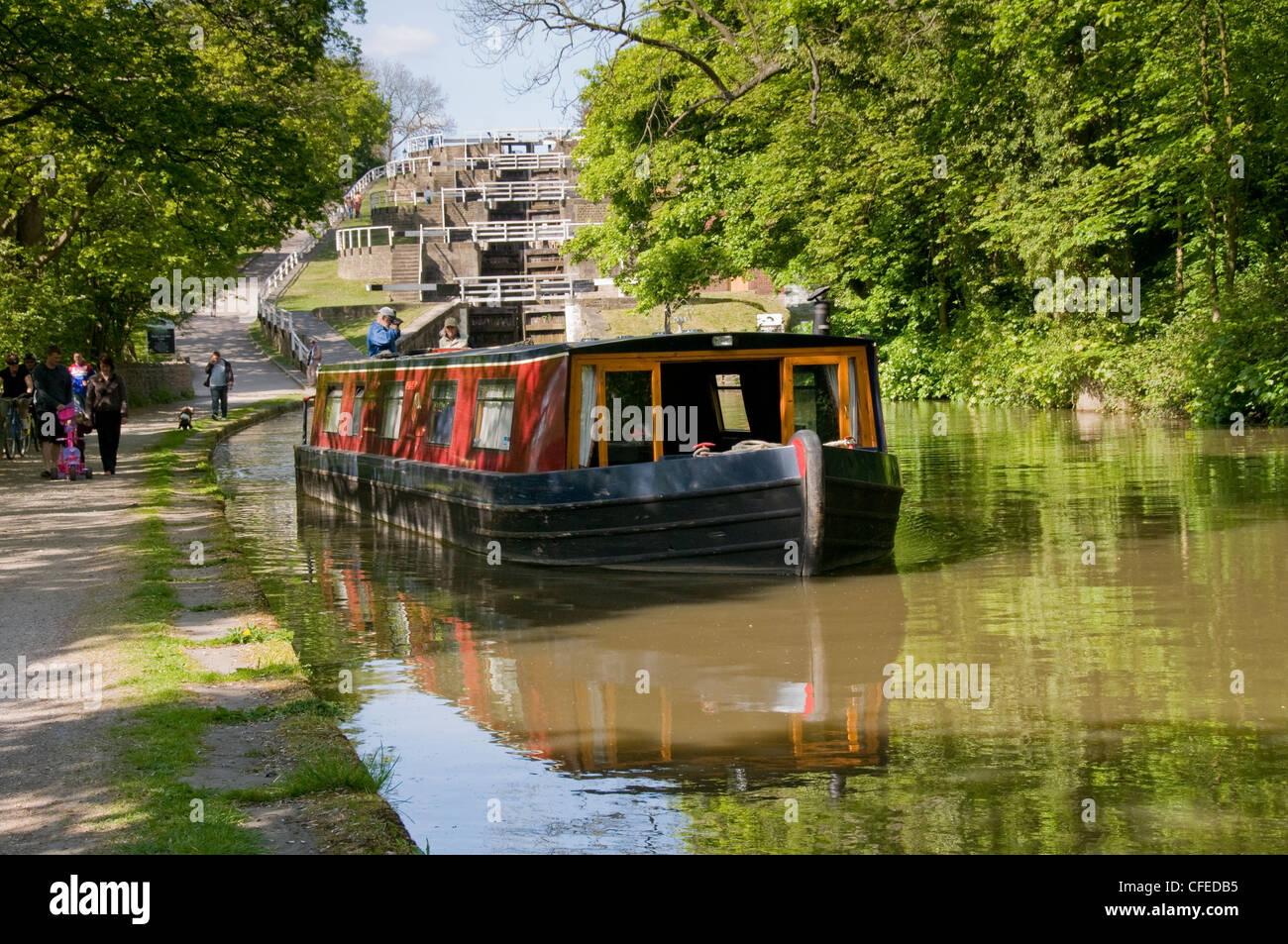 15-04 voyageant sur la voie d'eau en milieu rural (augmentation de cinq écluses, Leeds Liverpool Canal) avec l'homme & femme à bord - Bingley, West Yorkshire, England, UK Banque D'Images