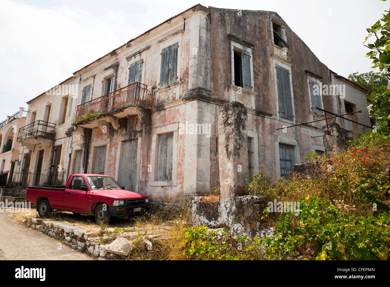 L'île de Céphalonie, grec, la Grèce, l'abandon typique maison abandonnée à Fiscardo avec camion stationné à l'extérieur rouge Banque D'Images