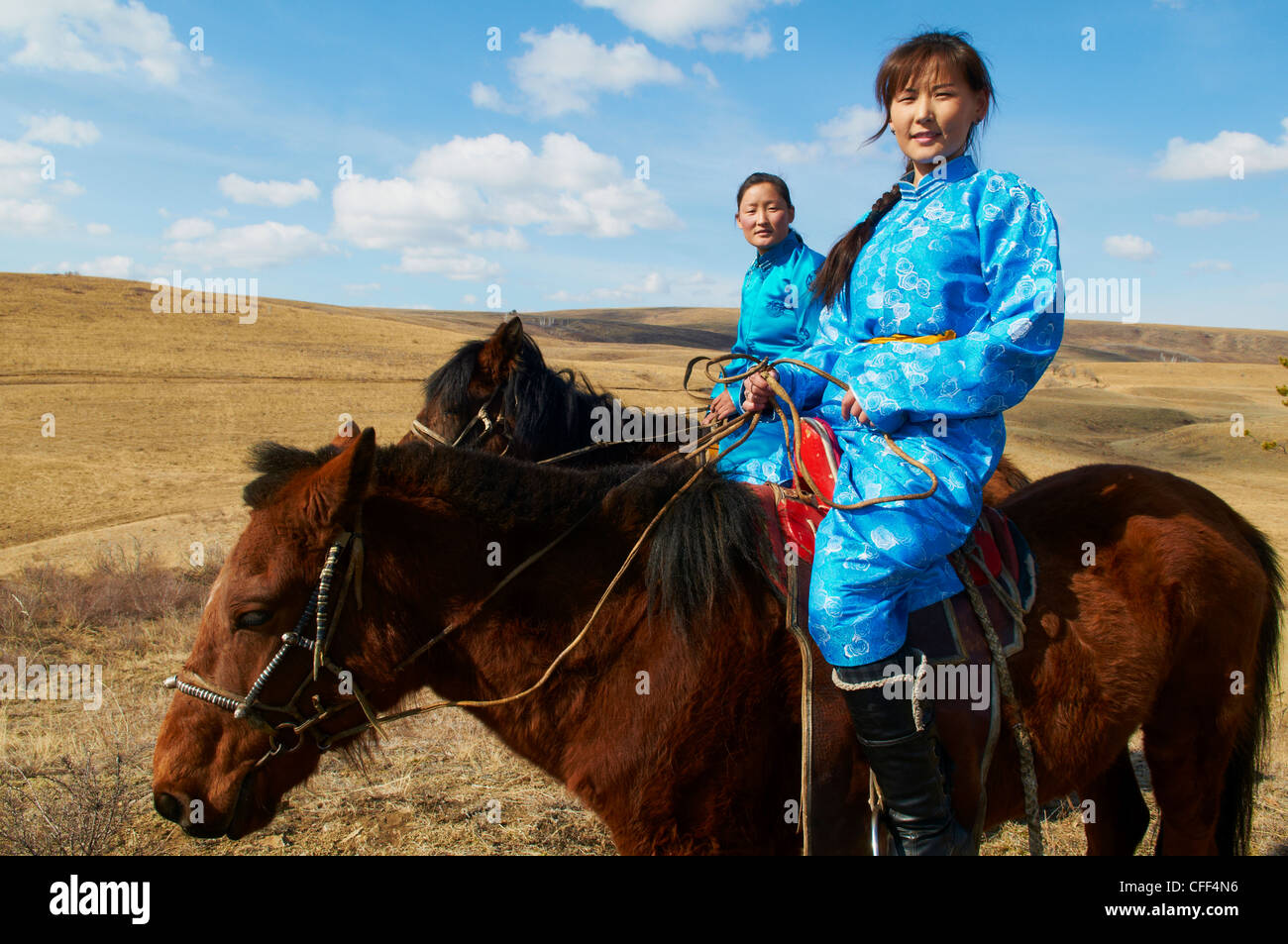 Les jeunes femmes en costume traditionnel mongol (deel) de l'équitation, province de Khovd, Mongolie, Asie centrale, Asie Banque D'Images