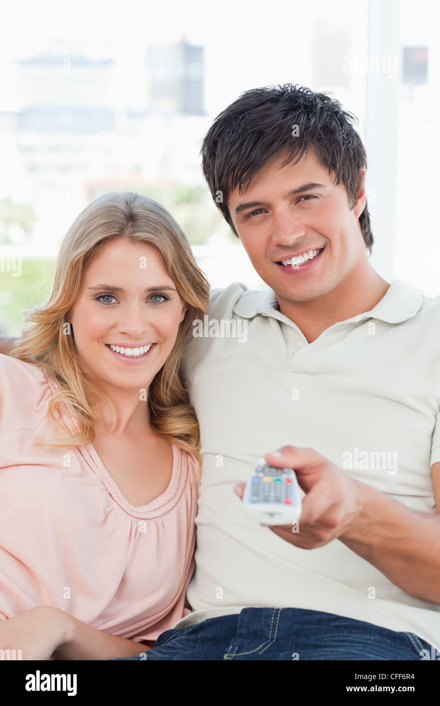 Close up, man and woman smiling car elles changent la chaîne tv Banque D'Images