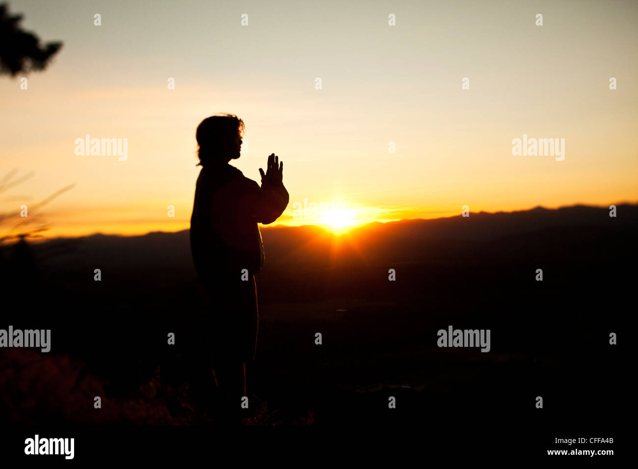 Un jeune homme qui prie que le soleil se lève sur une vallée de l'Idaho. Banque D'Images