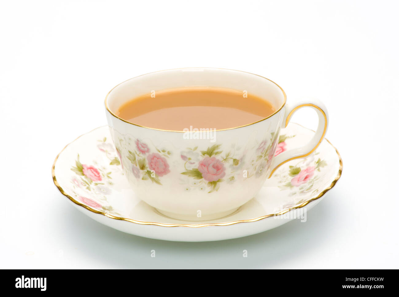 Tasse en porcelaine fleurie et soucoupe avec thé sur fond blanc. Banque D'Images