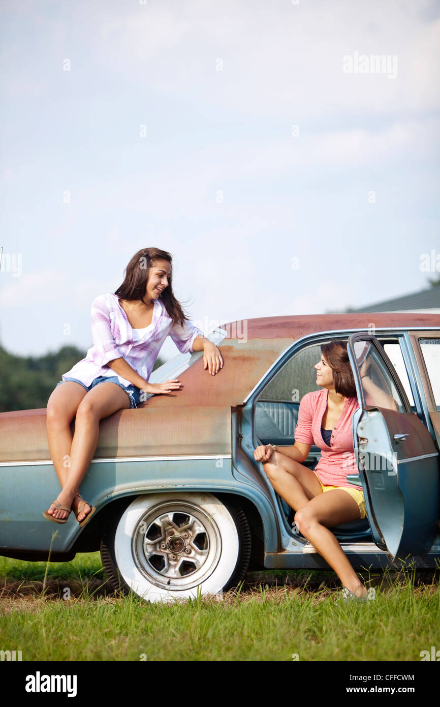 Deux soeurs se tenir sur une voiture classique. Banque D'Images