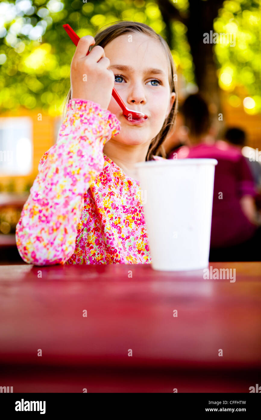 Une fillette de huit ans, mange la crème glacée tout en étant assis à la table de pique-nique, Garden City, Utah. Banque D'Images