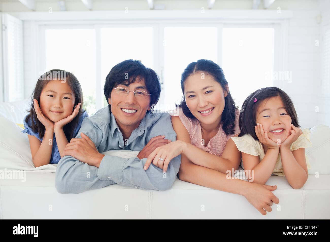 La famille sourire en s'agenouiller sur le canapé Banque D'Images