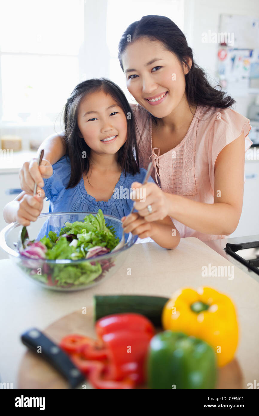 Smiling mother and daughter hâte comme ils jeter une salade Banque D'Images