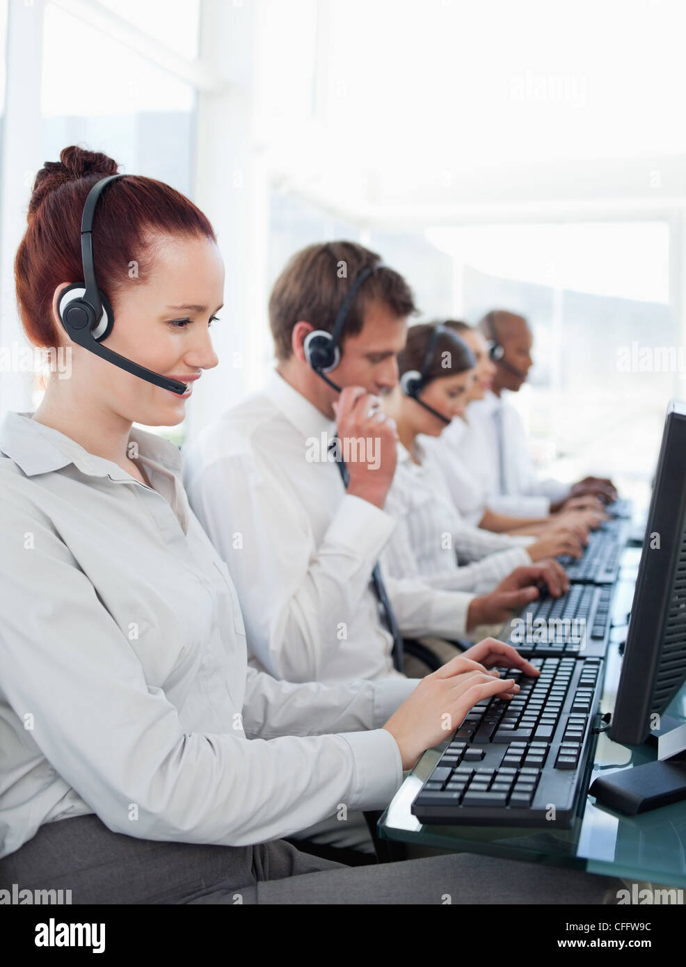 Les employés du centre d'appel de travail assis dans une ligne Banque D'Images