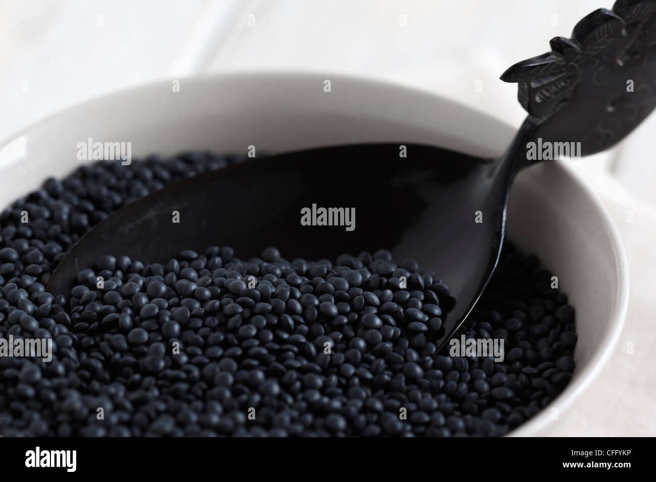 Lentilles Beluga noir dans un bol avec une cuillère en bois. Banque D'Images